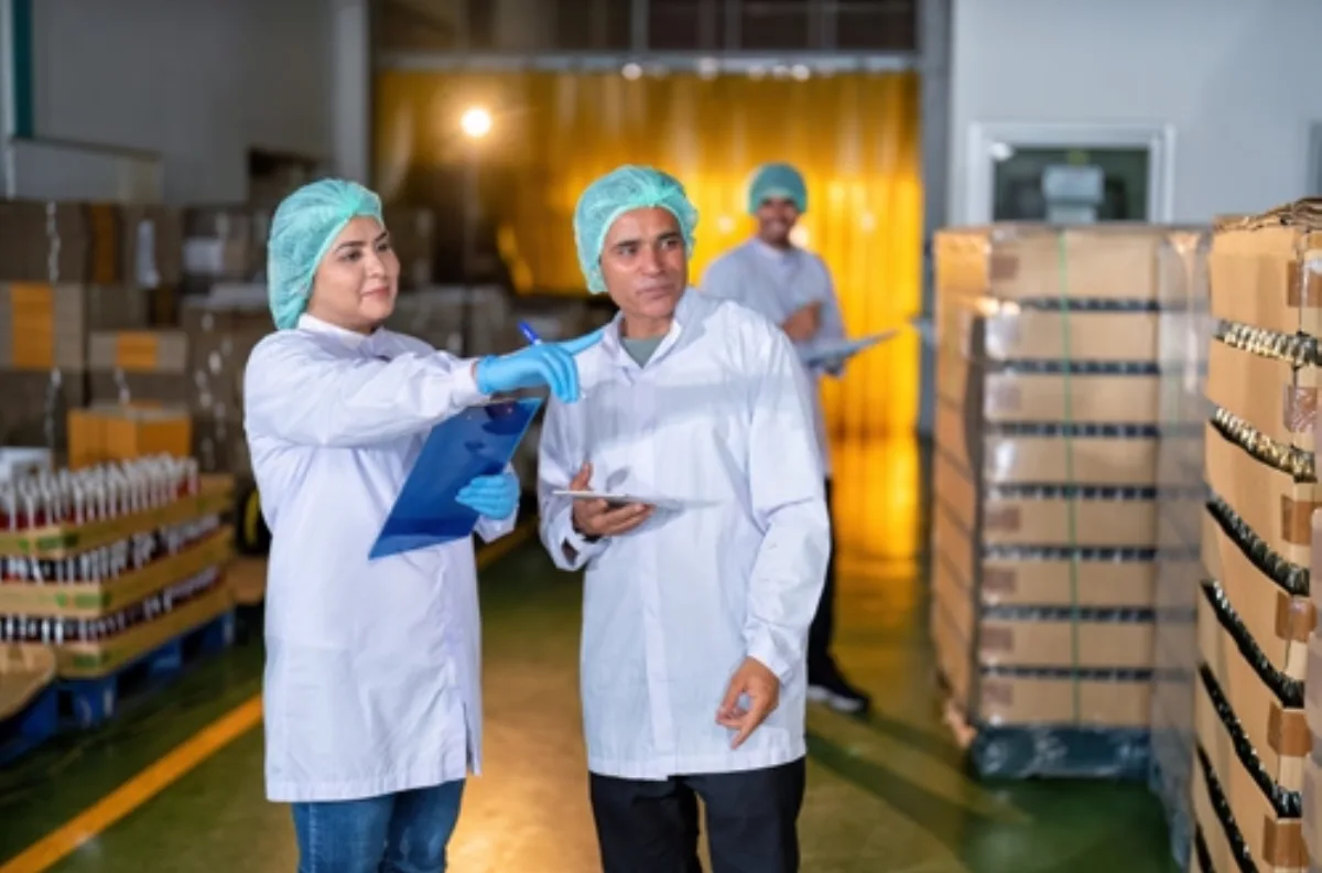 Two quality staff in coats and hairnets reviewing packaging in a cold chain warehouse