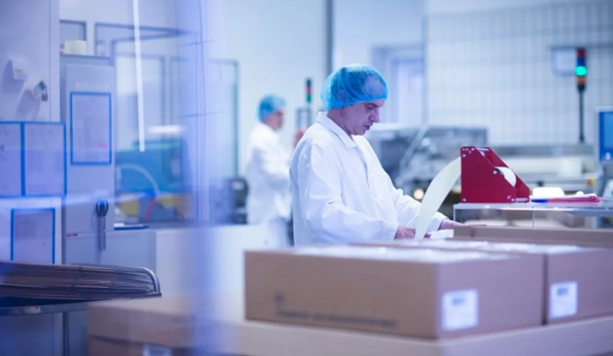 Technician in a cleanroom packing product into a cold chain shipping box